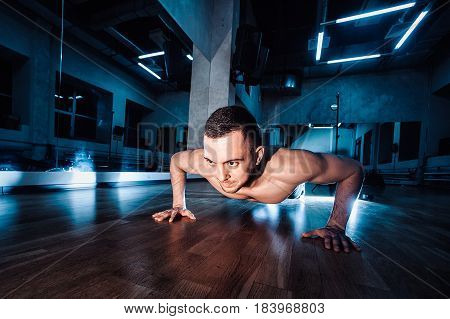 Attractive Muscular Man Doing Push-ups On A Wooden Floor.