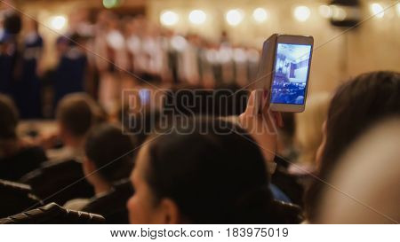 Audience in concert hall during performing piano girl- people shooting performance on smartphone, music opera, telephoto