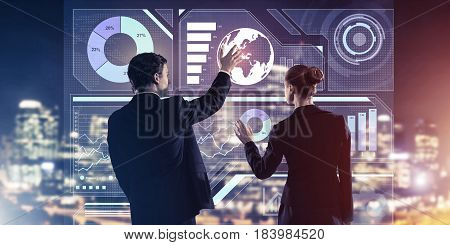 Two business people standing with back and working together with virtual screen
