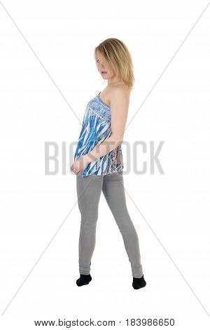 A beautiful young Caucasian woman standing from the back in gray jeans and blouse looking over shoulder isolated for white background.