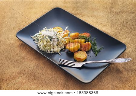 Baked potatoes with white cabbage salad n a black ceramic dish