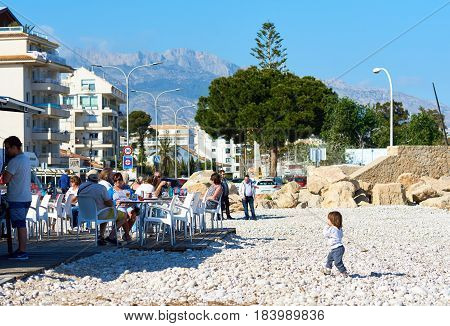 Altea Spain - April 8 2017: Pebble beach of Altea. People sitting in a outdoors cafe drinking refreshing beverages and enjoying view of resort town of Altea. Altea is the most beautiful place in the Costa Blanca. Spain