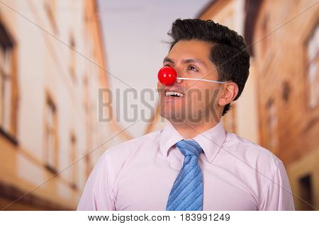 Funny handsome businessman with a red plastic nose got distracted