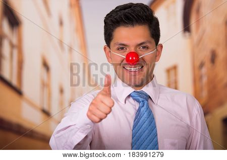 Funny handsome businessman with red plastic nose.