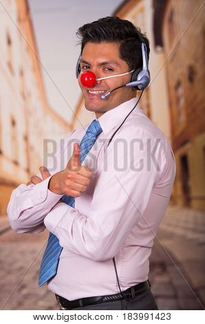 Funny handsome businessman with red plastic nose using headphones and he is looks surprised.