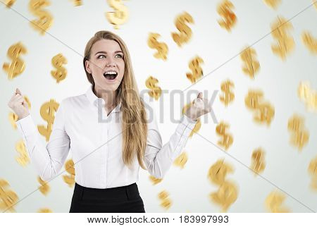 Portrait of a happy blond woman wearing a white shirt screaming with joy while standing against a gray wall with dollar signs