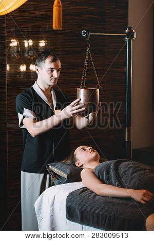Specialist Making Shirodhara Massage Form Of Ayurveda Therapy. Beautiful Woman Spending Time At Mode