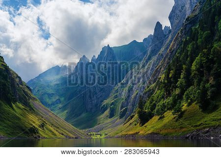 Mountain Landscape In The Swiss Alps With Jagged Peaks And A Pristine Blue Mountain Lake In The Vall