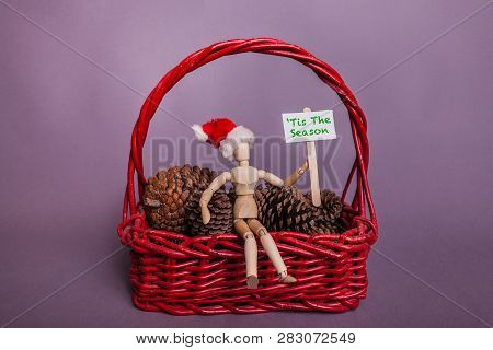 Tis The Sesion Picket Sign Held By Wooden Jointed Doll Figure Sitting In Large Red Basket Filled Wit