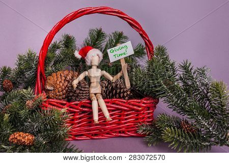 Giving Time Holiday Sign Held By Wooden Jointed Manikin Doll Sitting In A Red Basket Filled With Pin