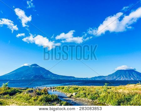 San Francisco River Flows Into Lake Atitlan With Atitlan, Toliman & San Pedro Volcanoes Behind In Ea