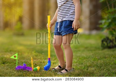 Little Girl Playing Mini Golf In Spring Park. Child Having Fun With Active Leisure On Vacations. Bab