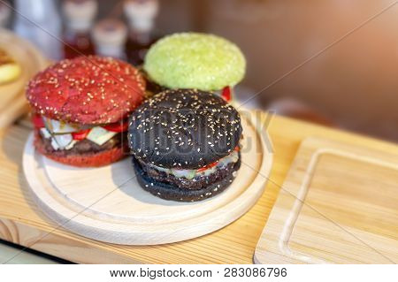 Three Tasty Bright Multicolored Beef Burgers On Wooden Counter At Food Fest. Amburger Bun Clolred Wi