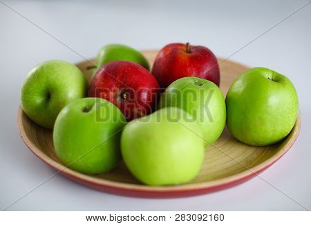 Green And Red Apple Lies On A White Table