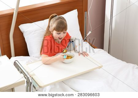 Little Child With Intravenous Drip Eating Soup In Hospital Bed