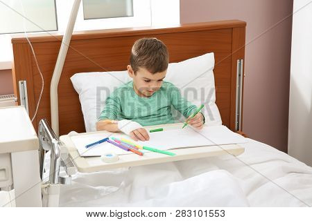 Little Child With Intravenous Drip Drawing In Hospital Bed