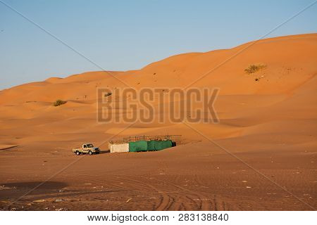Bidiyah, Oman - November 5, 2018: Animal Fence And Car Pickups Under Desert Dunes Wahiba Sands At Su