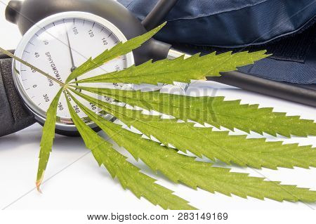 Cannabis Or Marijuana And Blood Pressure. Green Cannabis Leaf Lies Near Measuring Scale Of Sphygmoma