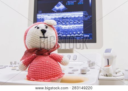 Medical Ultrasound Scanner And Children Toy Knitted Bunny On Screen Background With Waves Echo Heart