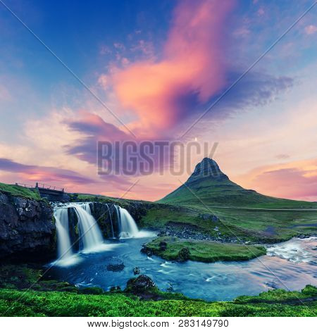 Colorful sunrise on Kirkjufellsfoss waterfall. Amazing morning scene near Kirkjufell volkano, Iceland