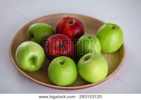 Green And Red Apple Lies On A White Table