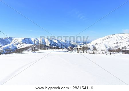 Winter Landscape With Snowy White Field, Mountains And Shelter. Sunny Day, Blue Sky. Piornedo, Ancar