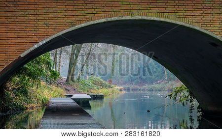 Jetty In The Water Under A Viaduct, The Park Of Hilversum, The Netherlands, Beautiful River Landscap