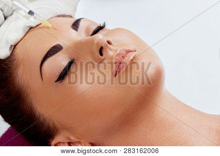 Portrait Of Beautiful Woman Gets Injection Of Botox In Her Lips. Closeup Hand In Glove With Syringe 