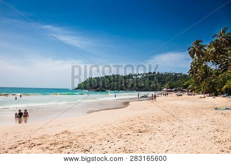 Mirissa Beach, Sri Lanka - JAN 2, 2017:  Tourists walking on the sand while enjoying the view across the wonderful beach of Mirissa on Jan 2, 2017. Sri Lanka.