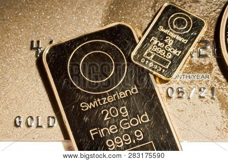 999.9 Gold Bars And A Fragment Of A Gold Coin On A Background Of A Gold Credit Card.