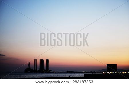 Silhouette Of Bridge Connected Offshore Oil Production Platforms At Oil Field During Sunset.