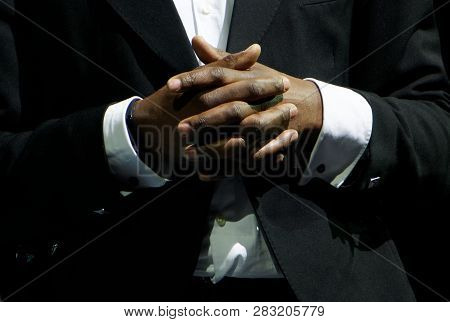 A Black Man In An Elegant Suit Clasp The Hands. Gestures And Features Of Business Negotiations. On A