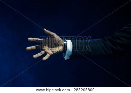 Hand Of A Black Man With An Open Palm. A Welcome Gesture For A Handshake. On A Dark Blue Background.