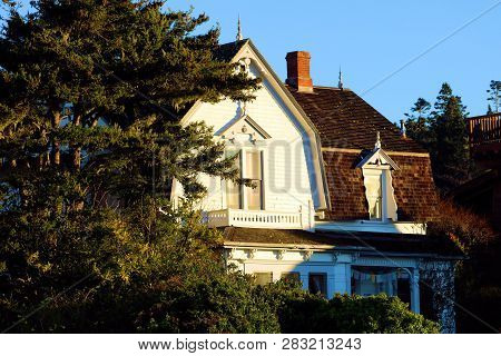 Vintage Colonial Style Home Surrounded By Manicured Plants And Trees Taken In A Coastal Beachside Co