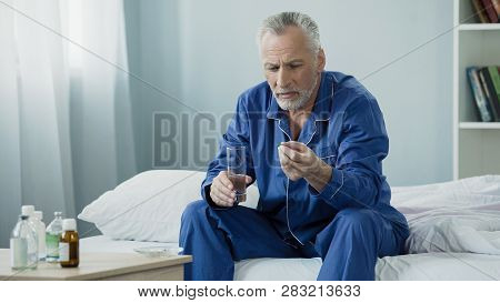 Male Pensioner Taking Daily Vitamin Complex To Maintain Genitourinary System