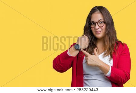 Beautiful plus size young business woman wearing elegant jacket and glasses over isolated background In hurry pointing to watch time, impatience, upset and angry for deadline delay