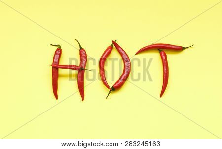 Word Hot In Capital Letters Filled With Red Hot Chili Peppers On Yellow Background. Minimal Fashion 