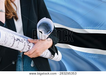 Architect Woman Holding Blueprint Against Botswana Waving Flag Background. Construction And Architec