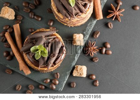 Dark Chocolate Cakes On Black Slattern Board With Mint, Cinnamon, Coffee Beans On A Wooden  Backgrou