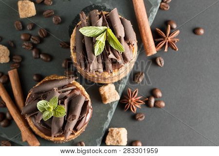Dark Chocolate Cakes On Black Slattern Board With Mint, Cinnamon, Coffee Beans On A Wooden  Backgrou