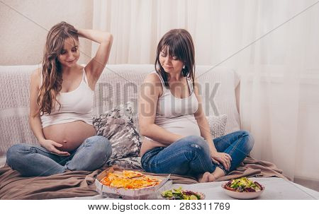 Two Pregnant Women Eating Pizza And Salad At Home