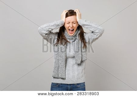 Exhausted Young Woman In Sweater, Scarf With Closed Eyes Screaming, Putting Hands On Head Having Hea