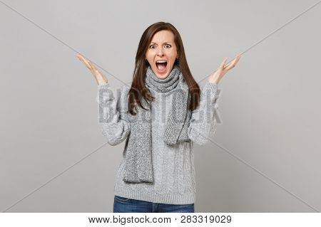 Shocked Young Woman In Gray Sweater Scarf Screaming, Spreading Hands Isolated On Grey Background In 