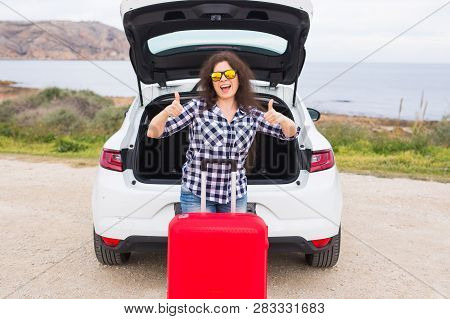 People, Vacation And Travel Concept - Young Woman With Suitcase Showing Thumbs Up Outdoors