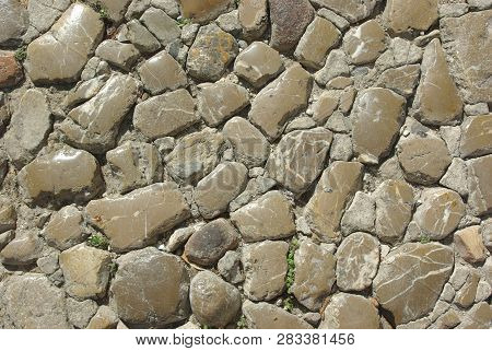 Fragment of an old city street pavement. Street paved by cobblestone. Cobbled texture
