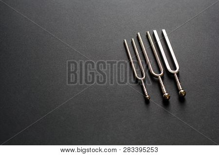 Three Tuning Forks On A Black Background