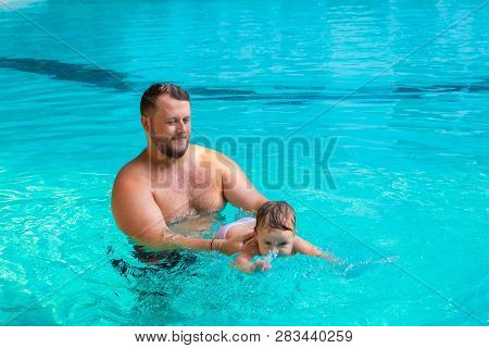 Dad Teaches A Child To Swim In The Pool. Father And Child Having Fun In The Pool. Dad And Daughter S