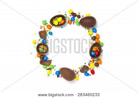 Broken And Whole Chocolate Eggs, Multi-colored Sweets On A White Background. Happy Easter. Circle Sh