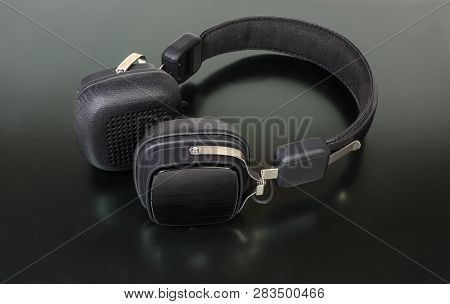 Black Wireless High-fidelity Ear Speakers On A Dark Matt Surface