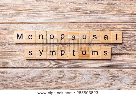 Menopausal Symptoms Word Written On Wood Block. Menopausal Symptoms Text On Wooden Table For Your De
